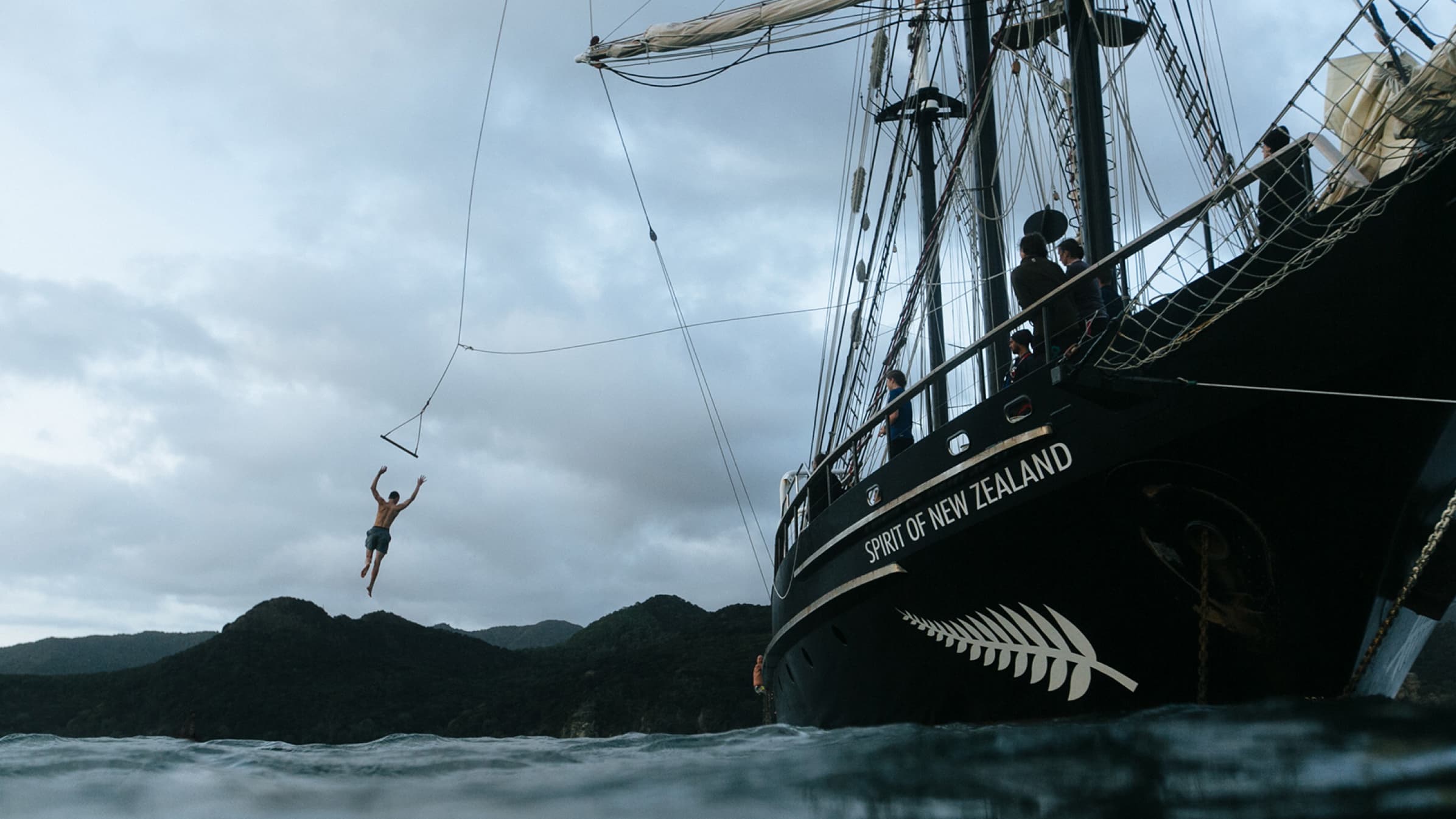 A passenger on the Spirit of Adventure jumps from a swing on the ship into the sea.